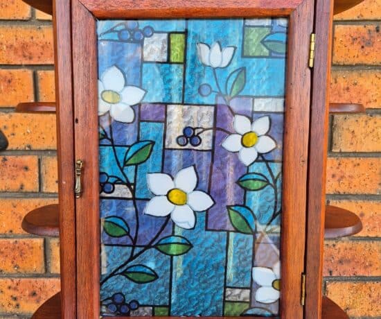 wooden vintage cabinet jewellery box with stained glass widow design sitting on a table.
