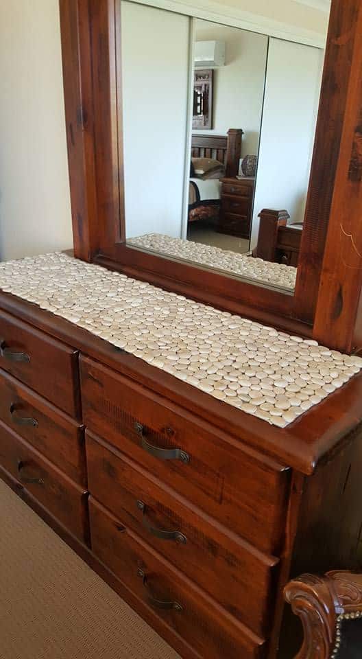 DIY pebble table runner used as a natural centrepiece on a wooden dresser