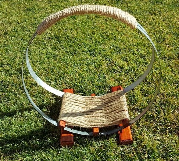 Firewood stand made from the bands from a wine barrel, with wood and sisal rope base.