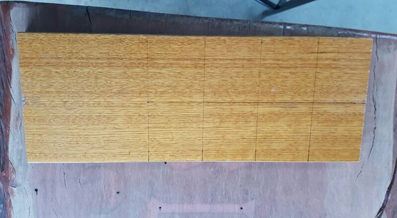 Darts laid out on timber board to measure spacing for wall-mounted stand