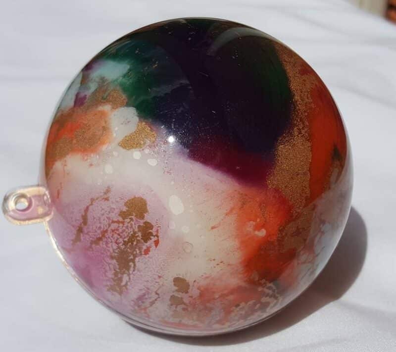 Close-up view of a marbled Unicorn Spit bauble with metallic gold highlights- multi coloured