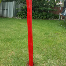 Candy cane striped PVC pipe drying outdoors for DIY Christmas signpost