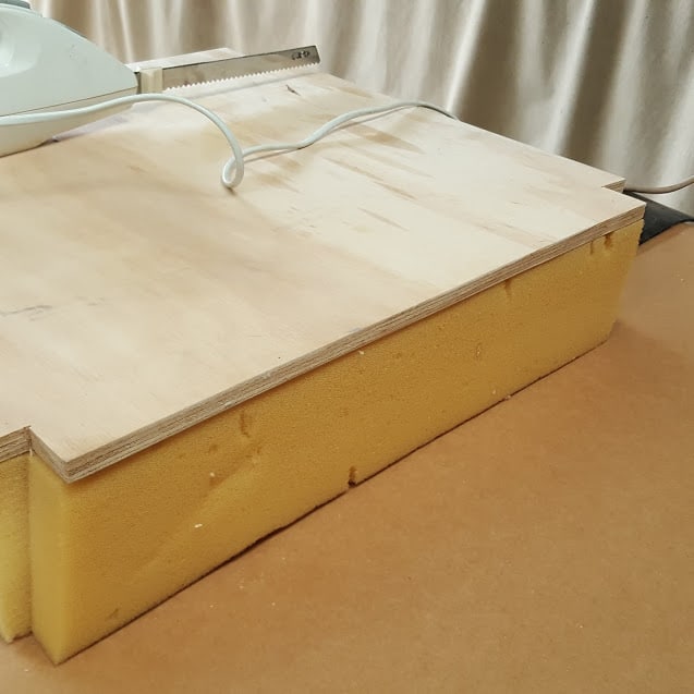 Foam seat being cut to fit over commode opening