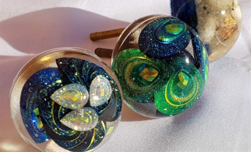 Finished resin door knobs with embedded plastic peacock beads.
