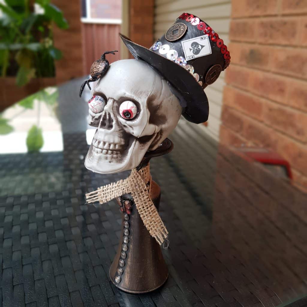 side view of skull with hat, spider and card.