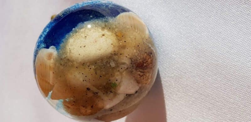 Resin door knob with ocean-blue resin, shells, and sand to mimic a beach scene.