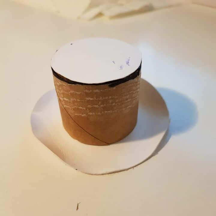 Toilet roll and cardboard being used to create miniature top hat.
