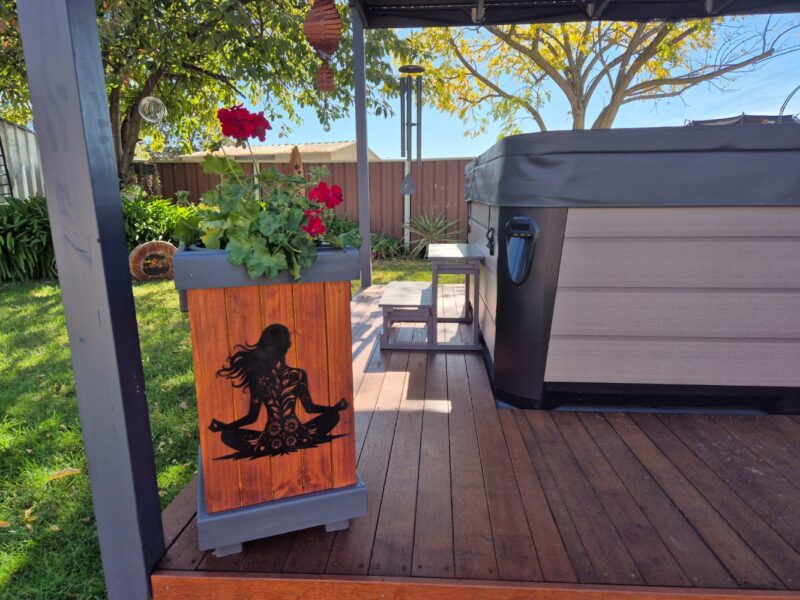 Red geranium in rustic wooden planter on spa deck